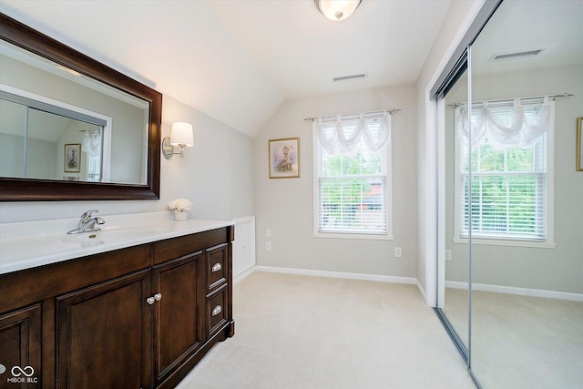 bathroom featuring plenty of natural light, vanity, lofted ceiling, and baseboards