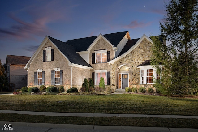 traditional-style home with stone siding and a front lawn
