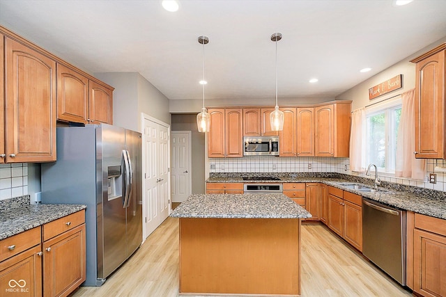kitchen with stainless steel appliances, a sink, light wood-type flooring, dark stone counters, and recessed lighting