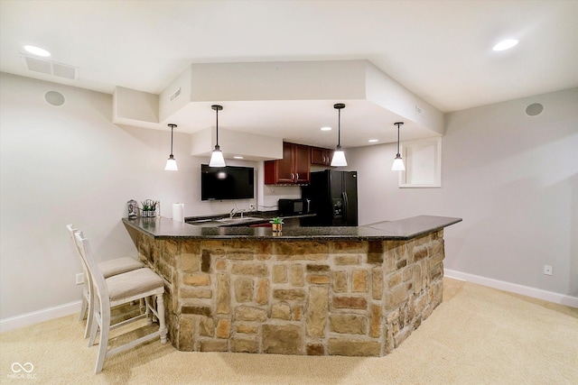 kitchen featuring black fridge with ice dispenser, light colored carpet, baseboards, a peninsula, and decorative light fixtures