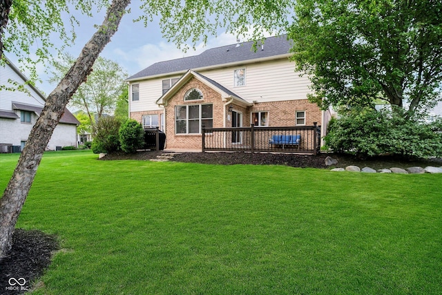 back of property with brick siding, a wooden deck, and a yard