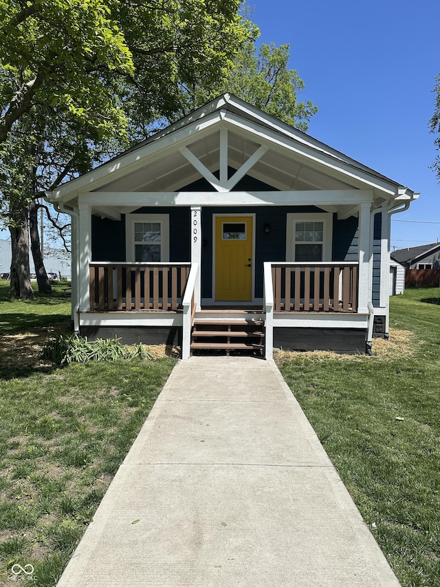 shotgun-style home with covered porch and a front lawn