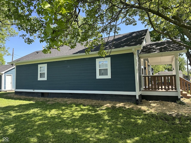 view of side of property with a lawn and a shingled roof