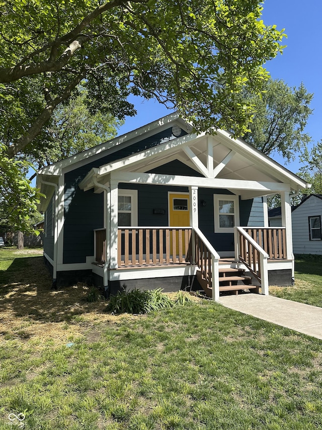 shotgun-style home featuring covered porch and a front lawn