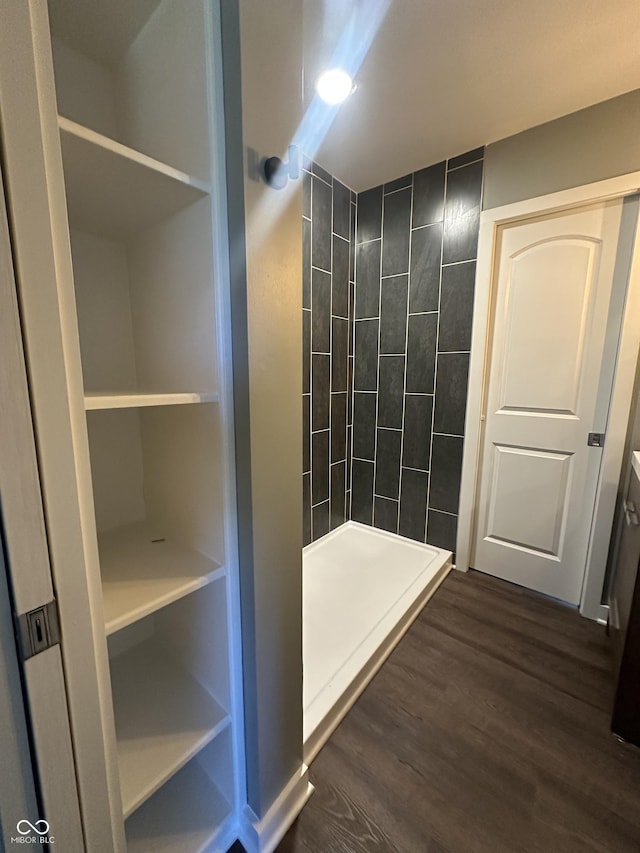 bathroom with tiled shower and wood finished floors