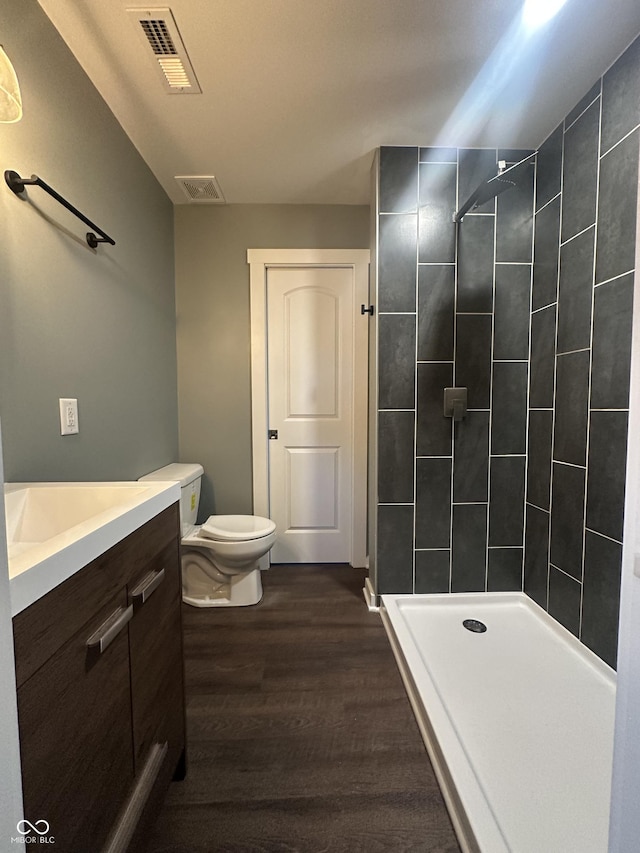 full bath with wood finished floors, a stall shower, vanity, and toilet