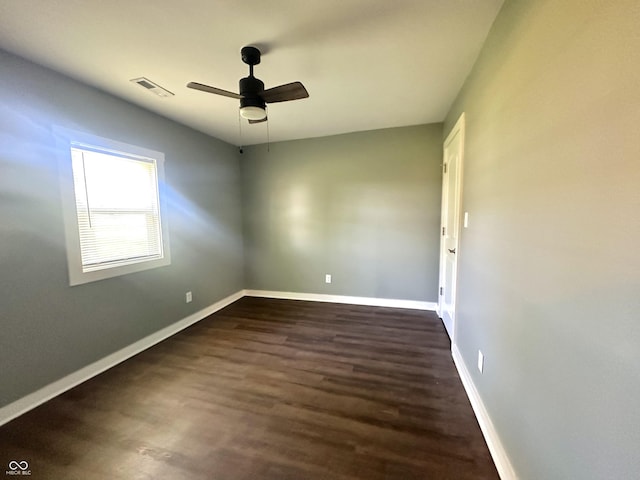 spare room with dark wood-style floors, a ceiling fan, and baseboards
