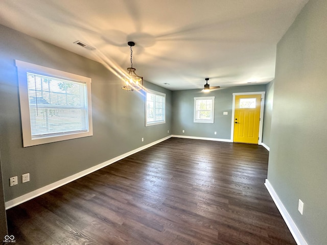 unfurnished dining area with dark wood finished floors, baseboards, and a ceiling fan