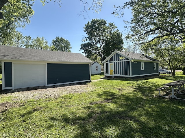 view of green lawn featuring an outdoor structure and a detached garage