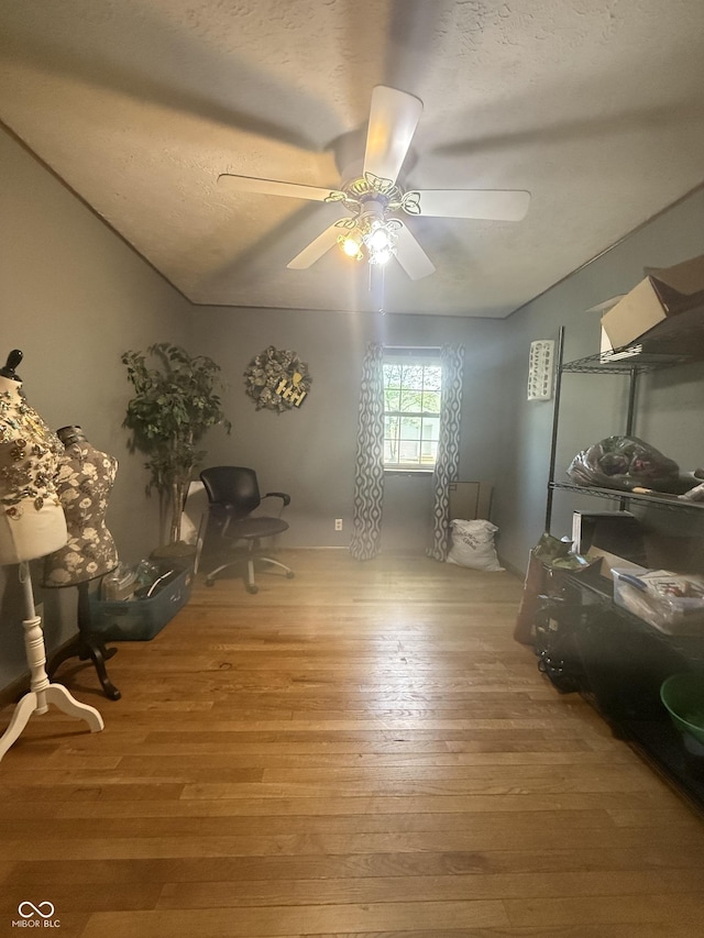 misc room featuring light wood-style floors, ceiling fan, and a textured ceiling