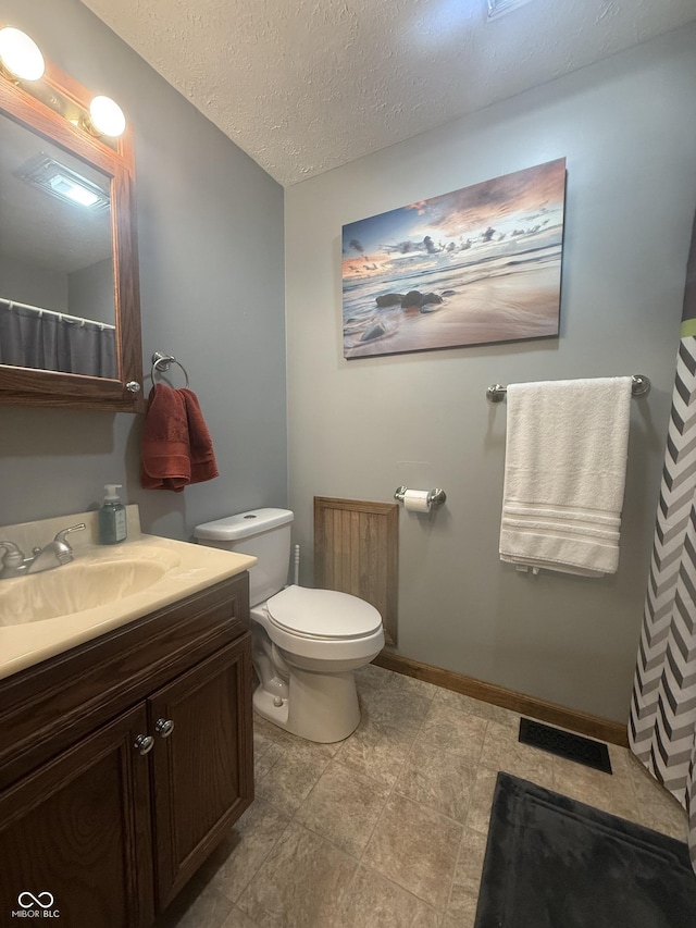 full bath with vanity, toilet, baseboards, and a textured ceiling