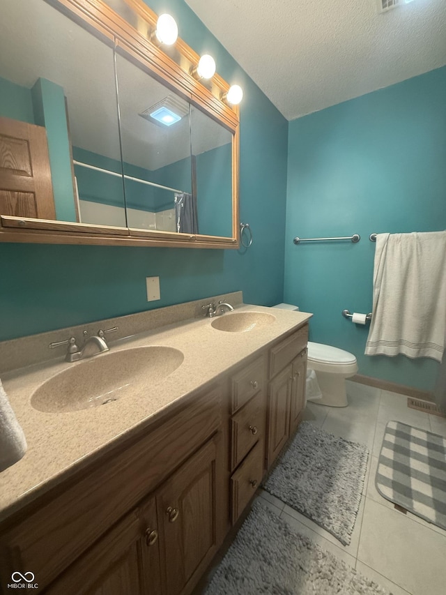 bathroom with tile patterned floors, a shower with shower curtain, toilet, double vanity, and a textured ceiling