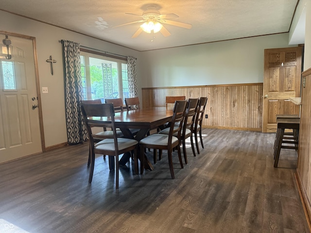 dining area with dark wood-style floors, wainscoting, ceiling fan, baseboards, and wood walls