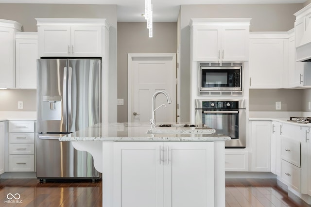 888 Westcreek Dr, Columbus, IN 47201 - kitchen with stainless steel appliances, white cabinets, dark wood-style floors, light stone counters, and a kitchen island with sink