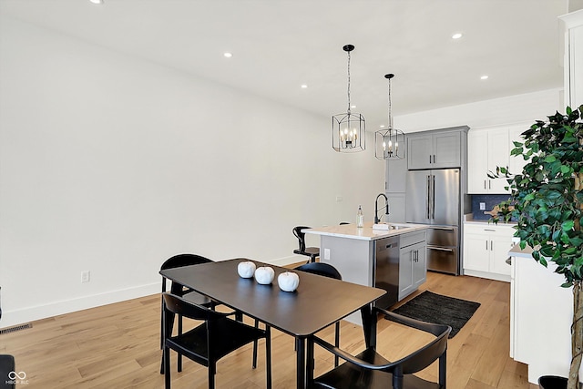 dining room with light wood-style flooring, recessed lighting, a chandelier, and baseboards
