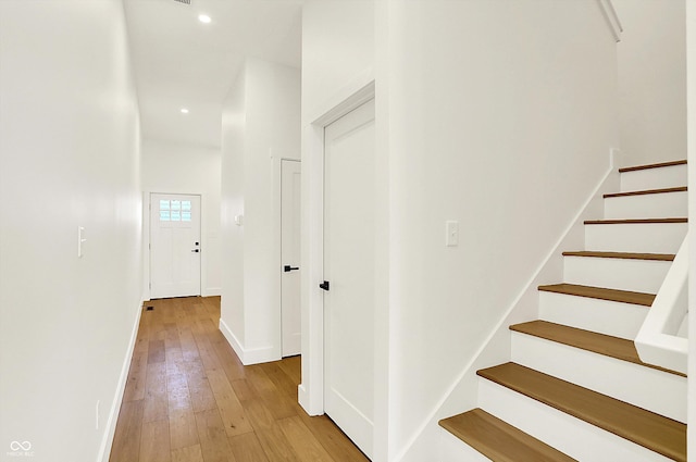 corridor featuring light wood-type flooring, stairs, baseboards, and recessed lighting