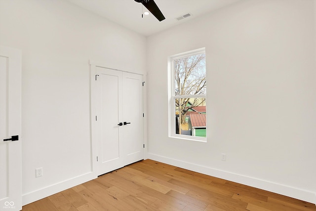 unfurnished bedroom with light wood-type flooring, baseboards, and a ceiling fan