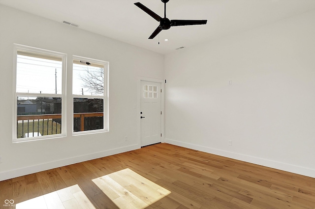 unfurnished room with a ceiling fan, baseboards, and light wood-type flooring