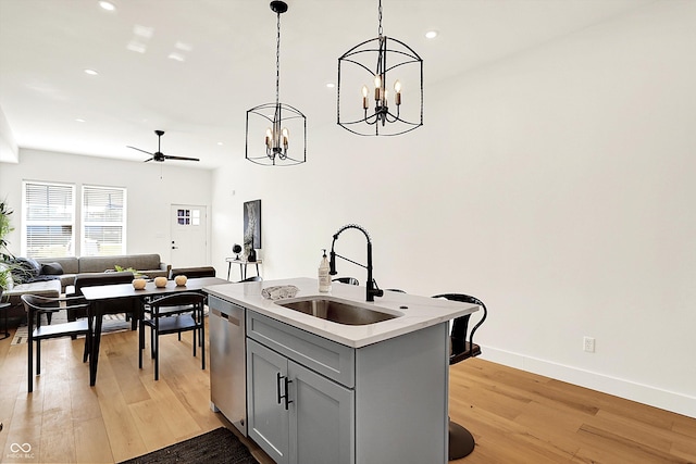 kitchen featuring a sink, dishwasher, gray cabinets, ceiling fan, and a chandelier
