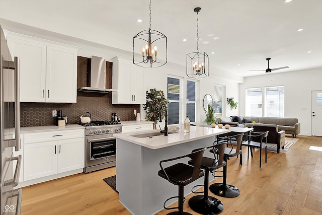 kitchen featuring wall chimney exhaust hood, appliances with stainless steel finishes, recessed lighting, open floor plan, and light countertops