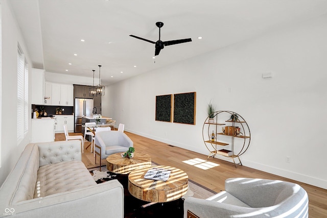 living area featuring light wood-style flooring, baseboards, recessed lighting, and a ceiling fan