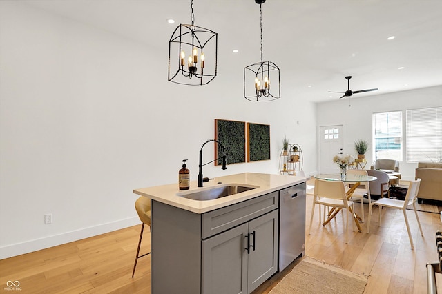 kitchen with stainless steel dishwasher, a sink, gray cabinets, open floor plan, and a ceiling fan