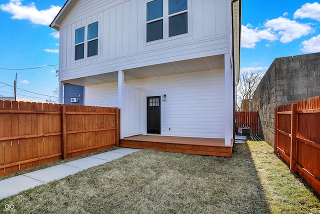 back of house with board and batten siding, a fenced backyard, central air condition unit, and a wooden deck