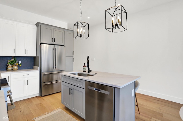 kitchen featuring stainless steel appliances, a sink, a chandelier, gray cabinets, and recessed lighting