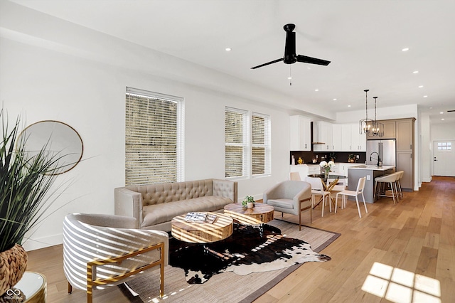 living room with ceiling fan, light wood-type flooring, recessed lighting, and a chandelier