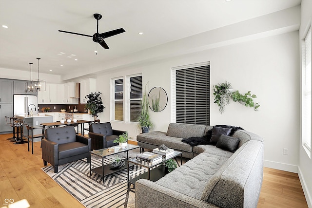 living area featuring ceiling fan, recessed lighting, light wood-style flooring, a chandelier, and baseboards