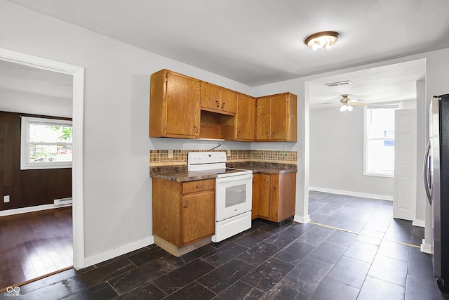 kitchen featuring electric range, brown cabinetry, freestanding refrigerator, dark countertops, and ceiling fan