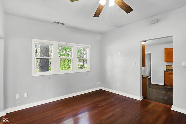 spare room with dark wood-style flooring, ceiling fan, and baseboards