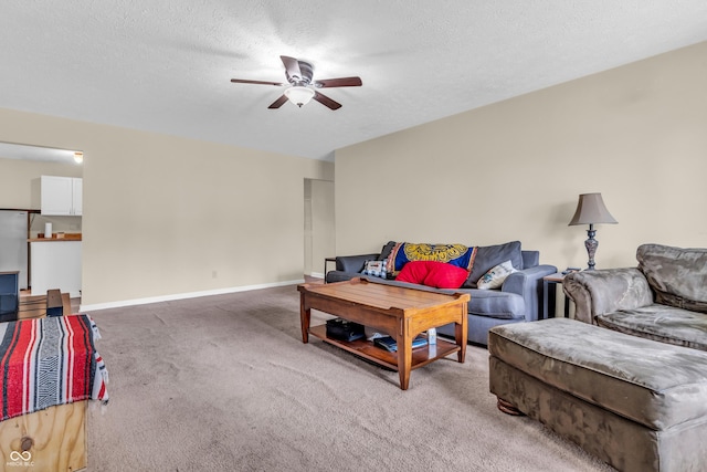 living area featuring light carpet, a ceiling fan, baseboards, and a textured ceiling