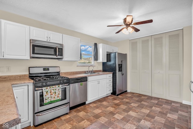 kitchen with appliances with stainless steel finishes, a sink, white cabinets, and a textured ceiling