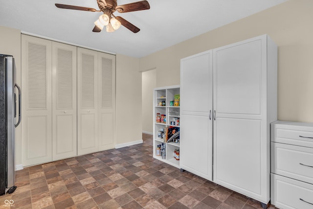 game room featuring a ceiling fan, dark stone finish flooring, and baseboards