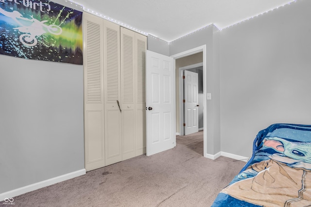 carpeted bedroom with baseboards and a closet