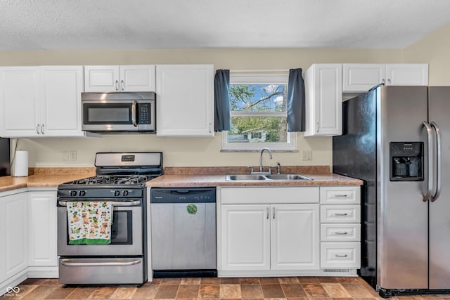 kitchen with stainless steel appliances, a sink, white cabinetry, and a textured ceiling