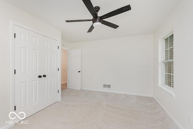 unfurnished bedroom featuring carpet floors, a closet, baseboards, and ceiling fan