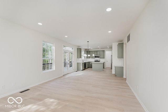 unfurnished living room with recessed lighting, light wood finished floors, and baseboards