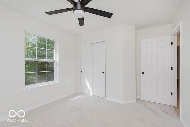 unfurnished bedroom with baseboards, a closet, light carpet, and a ceiling fan