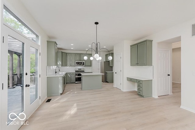 kitchen with stainless steel appliances, green cabinetry, a sink, light wood-type flooring, and recessed lighting