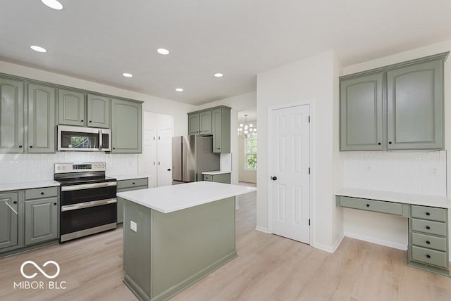 kitchen featuring stainless steel appliances, green cabinets, light wood finished floors, light countertops, and tasteful backsplash