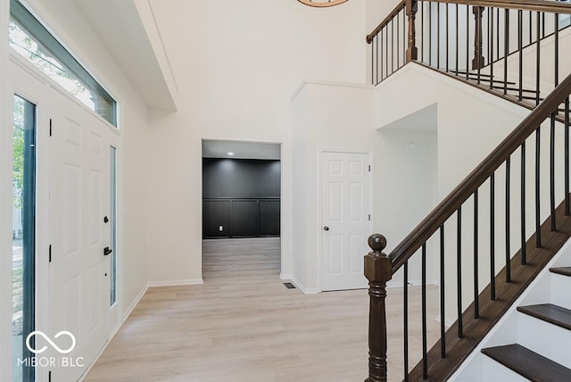 entryway with wood finished floors, a towering ceiling, stairs, and baseboards
