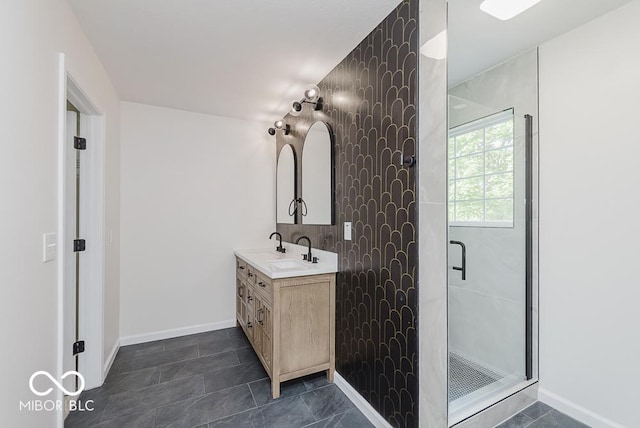 full bath with a shower stall, double vanity, and baseboards
