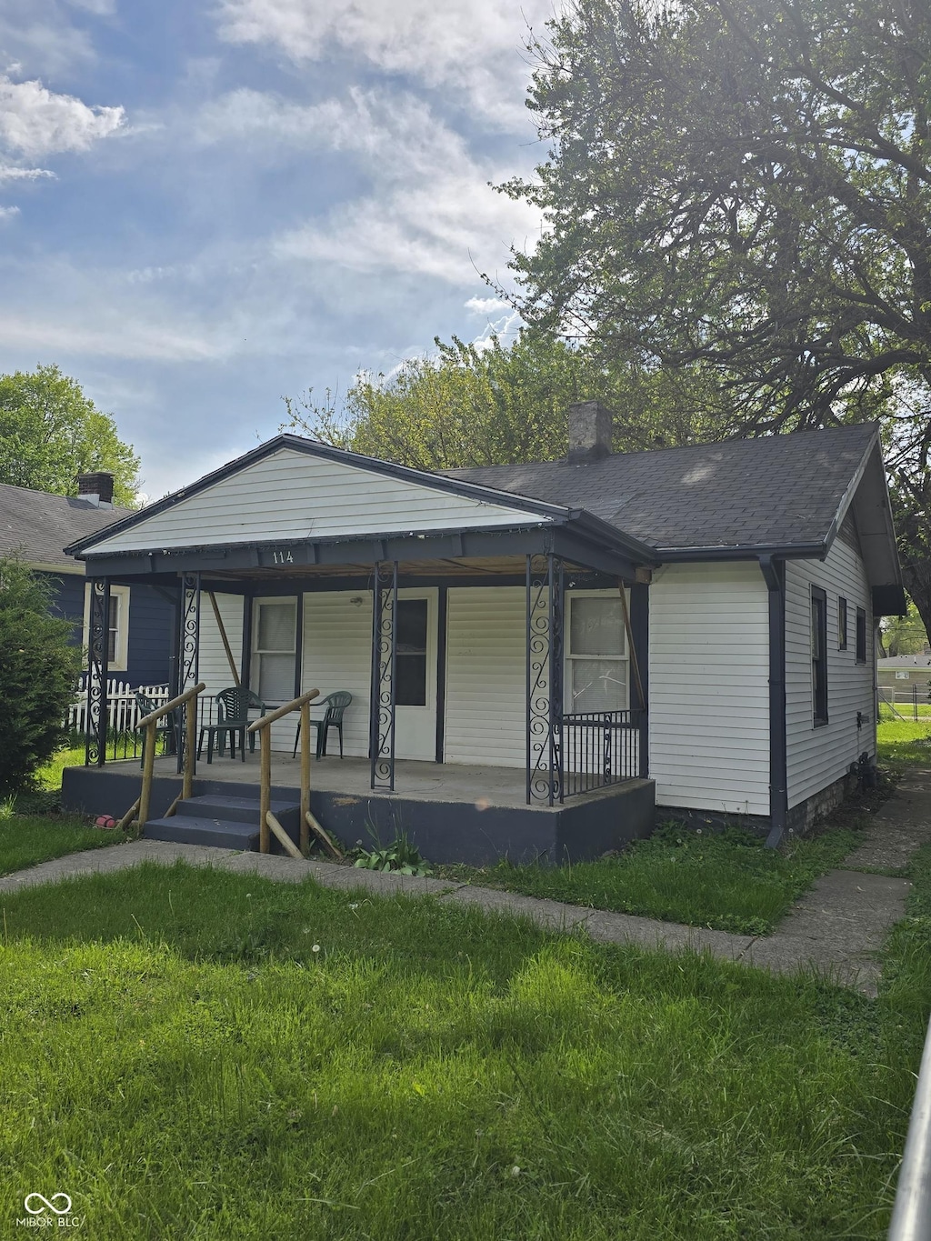 view of front of home featuring a porch, a front lawn, and a chimney