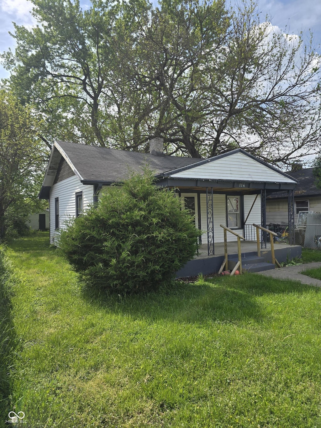 view of front of home featuring a porch, a front lawn, and a chimney