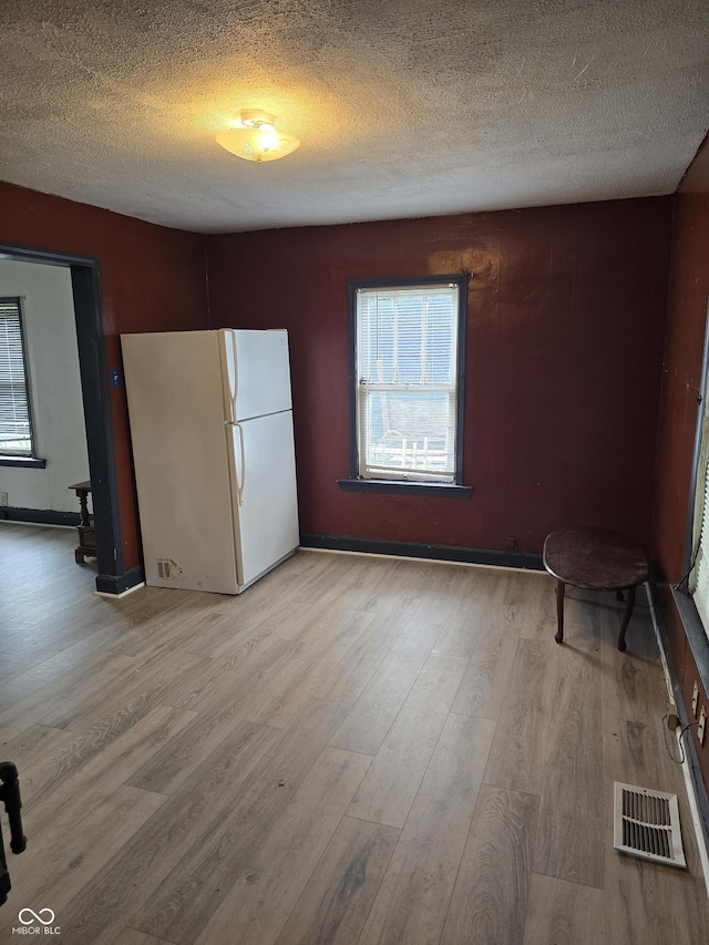 114 S Catherwood Ave, Indianapolis, IN 46219 - unfurnished dining area featuring light wood-style flooring, a textured ceiling, and baseboards