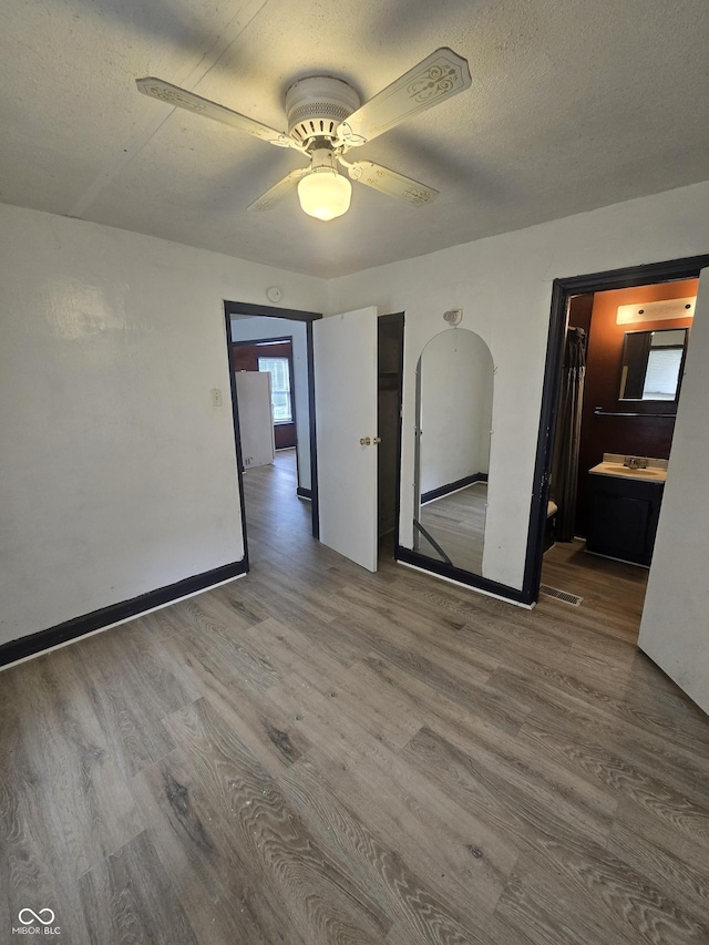 114 S Catherwood Ave, Indianapolis, IN 46219 - unfurnished room featuring wood finished floors, baseboards, a ceiling fan, arched walkways, and a textured ceiling