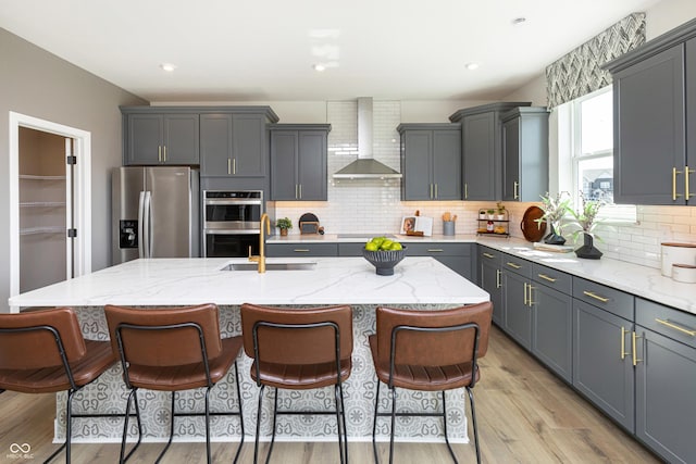175 Rock Island Rd, Westfield, IN 46074 - kitchen featuring stainless steel appliances, wall chimney range hood, light wood-style flooring, a kitchen island with sink, and backsplash