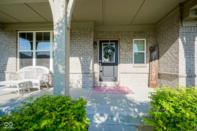 doorway to property featuring brick siding and a porch